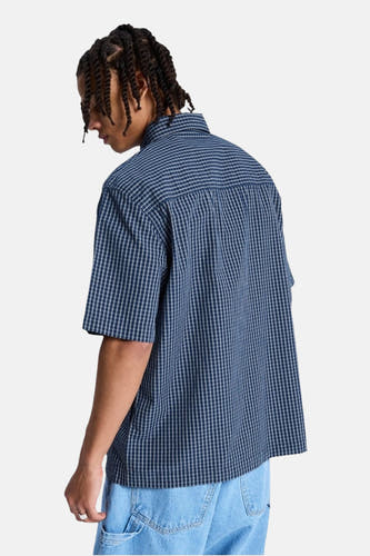 Blauw geruit hemd met korte mouwen van DC SHOES, aan de achterkant gedragen door een persoon met twists en lichtblauwe jeans.