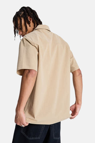 Bruin overhemd met korte mouwen van DC SHOES, gezien van achteren, met een gladde textuur en gedragen met een donkere broek.
