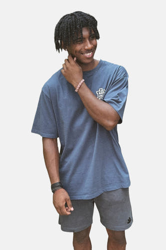 T-shirt bleu à manches courtes de BASELAB, porté avec des short gris et des bracelets.