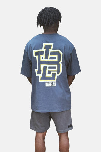 T-shirt bleu à manches courtes de BASELAB, avec logo sur le dos, porté avec des shorts gris.