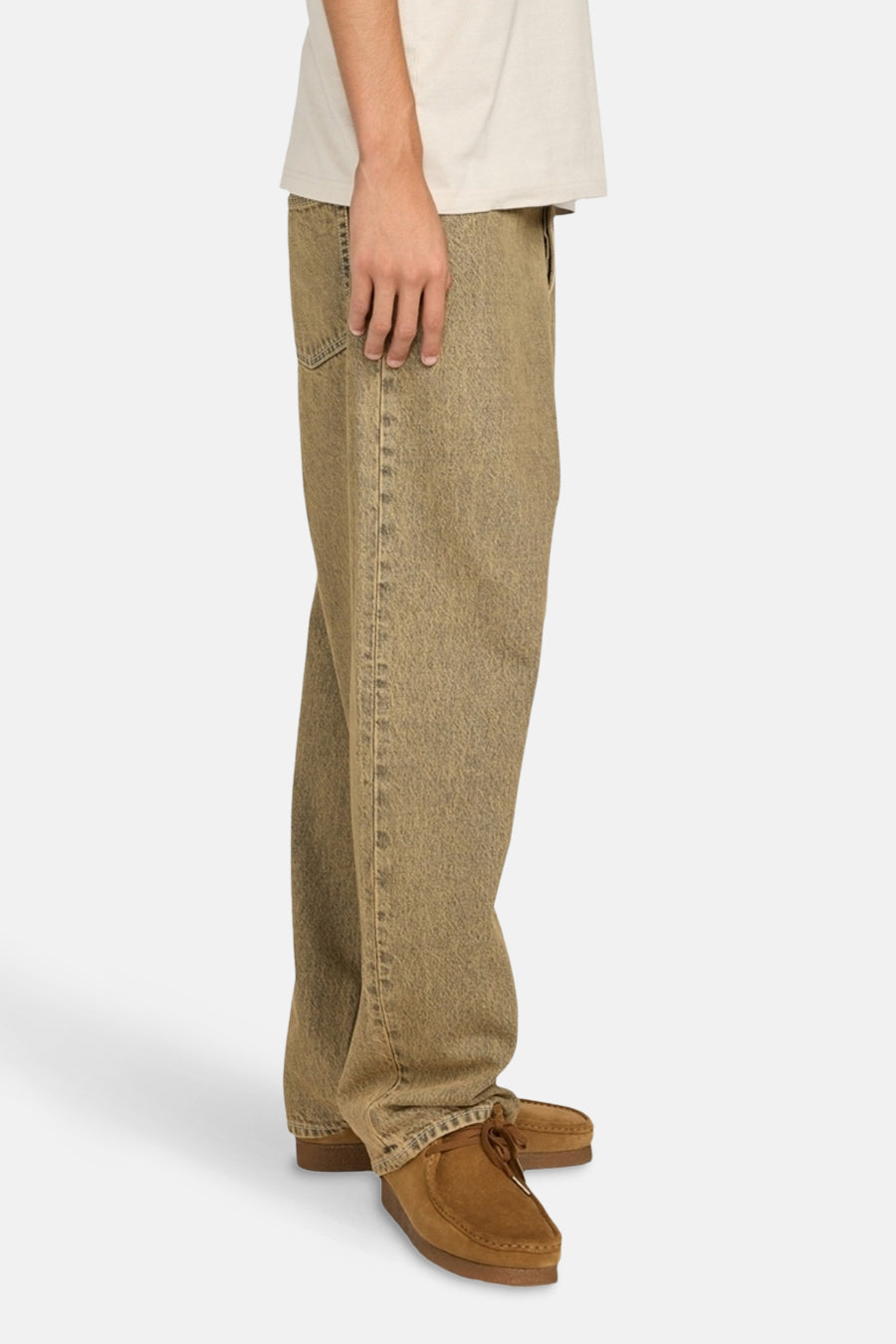 Een persoon die een beige T-shirt en bruine broek draagt met bruine schoenen.
