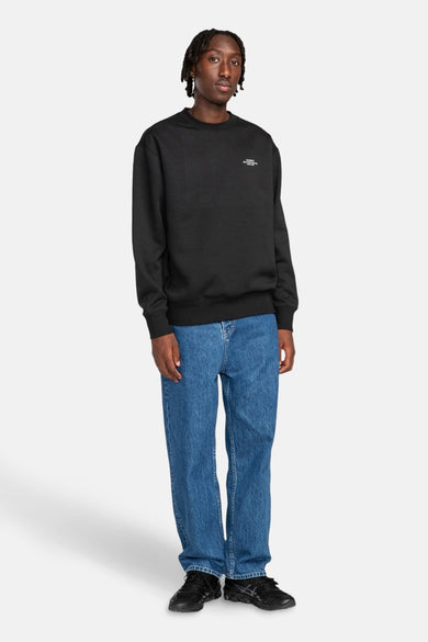 Pull-over noir d'ELEMENT, avec des manches longues et associé à des jeans bleus et des chaussures noires.