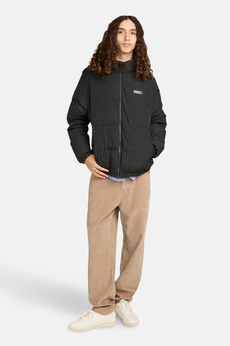 Manteau court noir d'ELEMENT, porté avec un pantalon de corduroy et des baskets blanches.