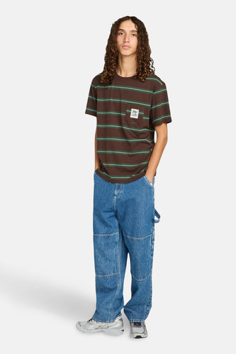 Jonge man in bruin gestreept T-shirt, blauwe jeans en grijze sneakers.