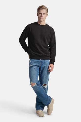 Zwarte sweater van ELEMENT, met lange mouwen, gecombineerd met gescheurde jeans en beige sneakers.