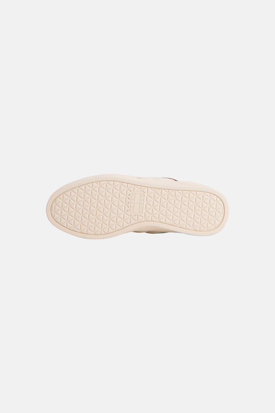 Baskets blanches TOMMY JEANS, avec une semelle beige clair à motif triangulaire géométrique et des lettres de marque verticales.