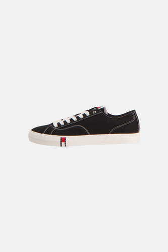 Baskets noires de TOMMY JEANS, avec lacets et semelle blancs, et logo sur le côté.