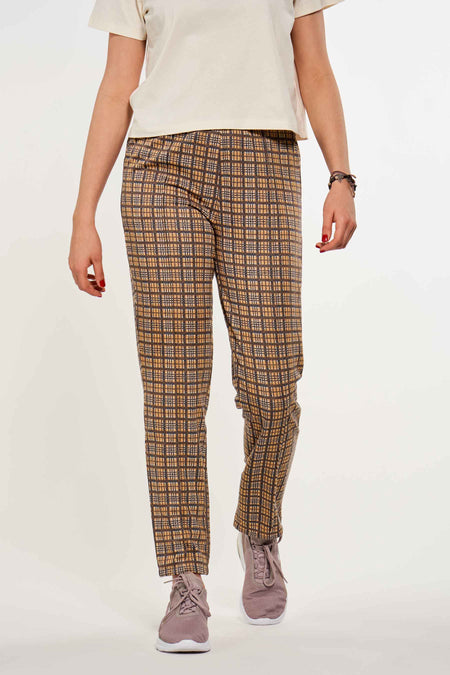 Roze broek 7/8 van CEMI by Céline & Michiel, met een bruin geruit patroon en gecombineerd met een wit shirt en roze sneakers.
