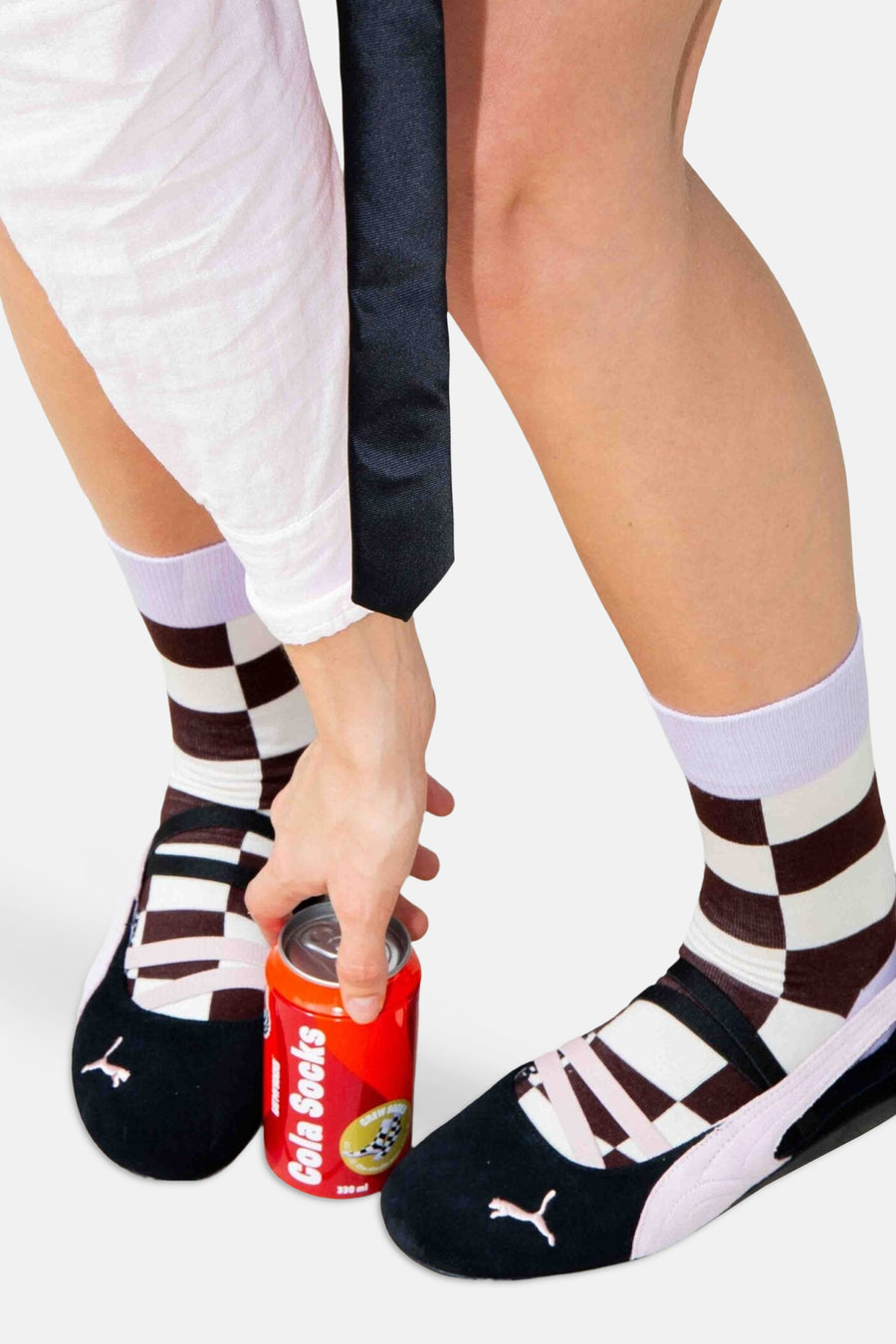 Rode sokken met schaakbordpatroon van EAT MY SOCKS, gedragen met zwarte balletschoenen en witte broek, lifestyle shot met cola-blikje