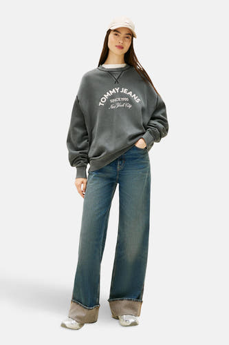 Sneakers gris de Tommy Jeans, avec des détails argentés et des jeans bleus larges à revers.