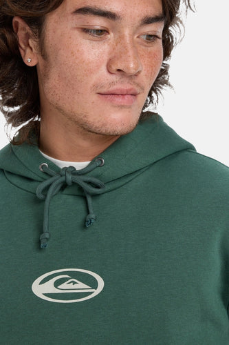 Close-up van een man met een groene hoodie en wit logo.