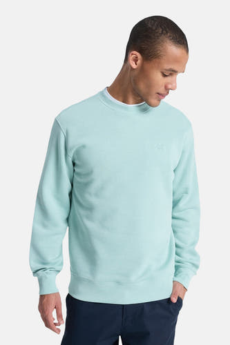 Pull bleu clair Quiksilver, à manches longues et col rond, porté avec un pantalon bleu foncé.