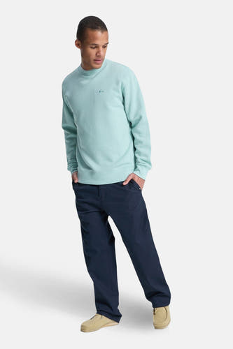 Pull bleu clair Quiksilver, à manches longues et col rond, combiné avec un pantalon foncé et des chaussures en daim.