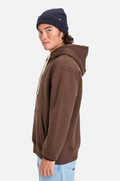 Pull-over marron avec capuche Quiksilver, doté d'une corde de tirage et d'une poche à l'avant, porté avec une bonnet bleu.