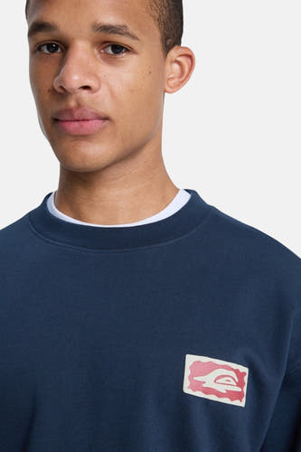 Blauwe sweater met ronde hals van Quiksilver, met een klein rechthoekig logo op de borst.
