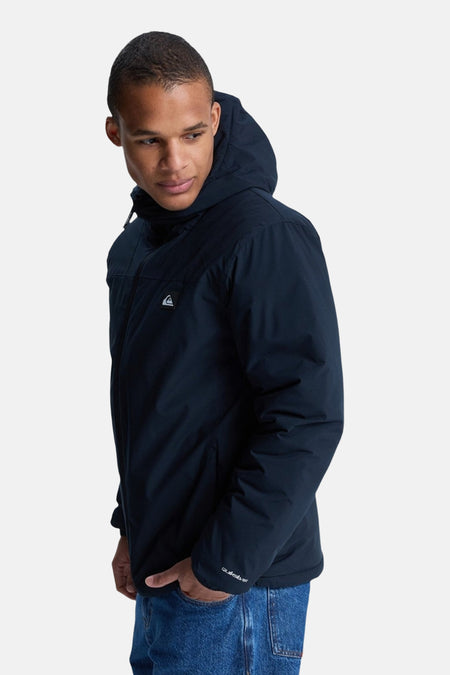 Manteau court noir de Quiksilver, avec capuche et jeans bleus.