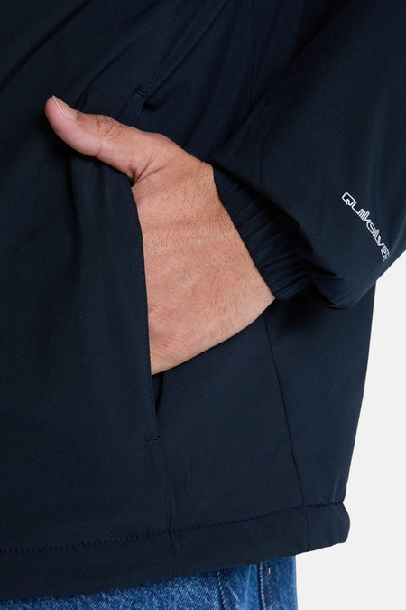 Veste courte noire de Quiksilver, avec une main dans la poche et le logo sur le manchon.
