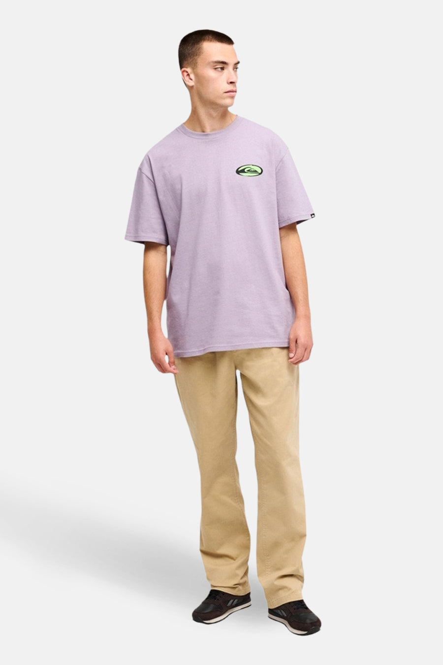 Pantalon beige de Quiksilver, combiné avec un t-shirt violet à logo et des chaussures noires.
