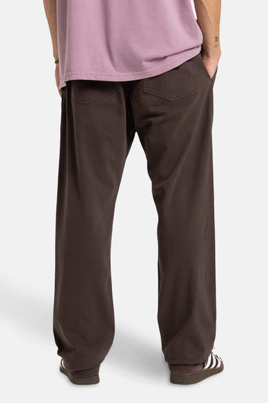 Pantalon brun de Quiksilver, vu de l'arrière avec des poches et un chemisier rose.
