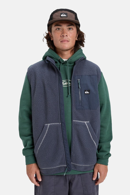 Gilet Quiksilver de couleur bleue avec une texture en polaire et un hoodie vert en dessous.