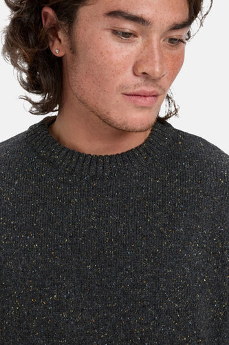 Man met sproeten draagt grijze wollen trui.
