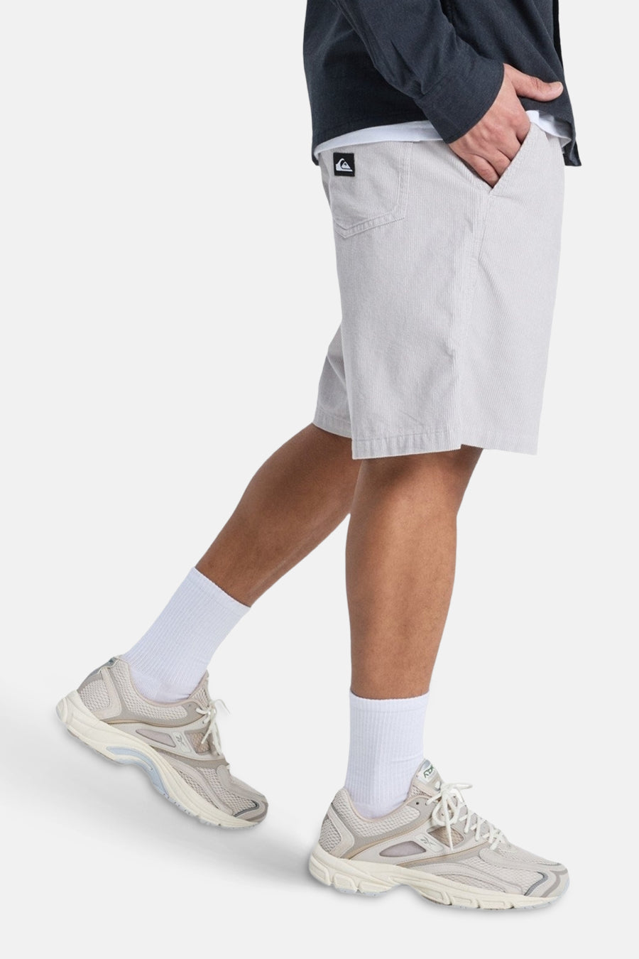 Grijze short van Quiksilver, met een fijne streeptextuur, gedragen met witte sokken en crèmekleurige sneakers.
