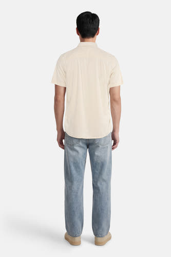Chemise écru à manches courtes de Quiksilver, vue de dos avec une texture unie et un jean bleu.