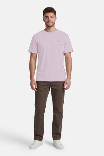 T-shirt violet de Quiksilver avec petit logo sur la poitrine, porté par un homme avec un pantalon marron et des baskets blanches.