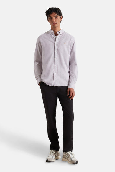 Pantalon noir de Farah, associé à un chemisier rayé et des baskets.