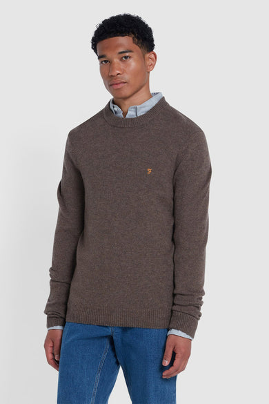 Pull marron avec col rond de FARAH, porté sur une chemise bleu clair et associé à des jeans bleus.