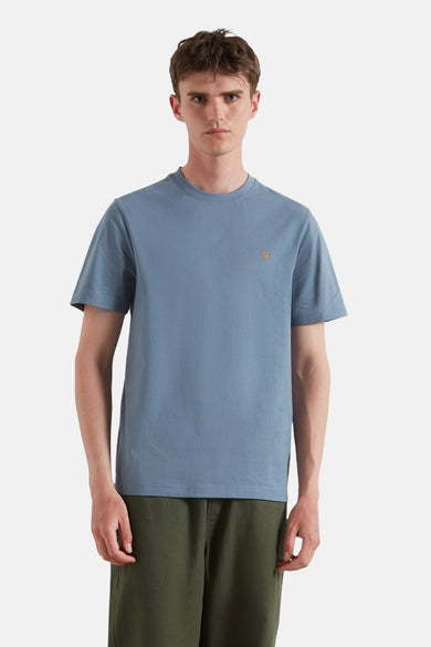 T-shirt bleu à manches courtes de FARAH, avec un petit logo sur la poitrine et associé à un pantalon vert olive.
