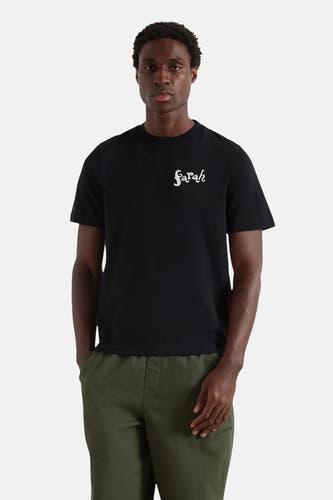 T-shirt noir à manches courtes de Farah, avec du texte "Sarah" blanc sur la poitrine, porté avec un pantalon vert.