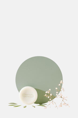 Produit de soin vert WONDR CARE, avec décoré de fleurs blanches et de feuilles vertes.