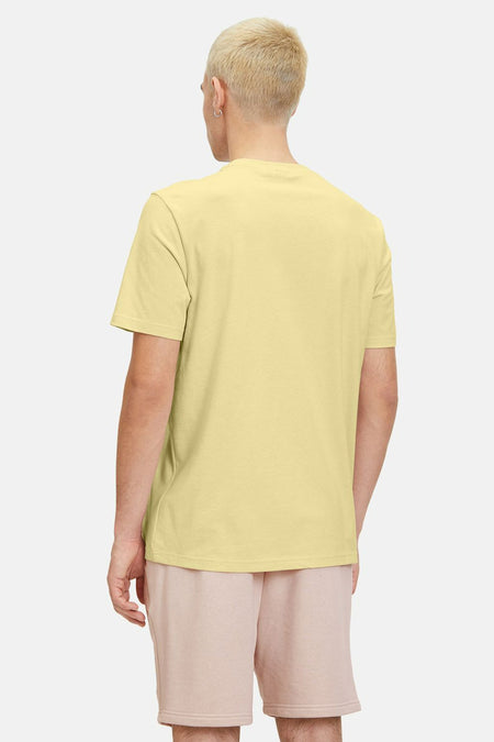 Geel T-shirt met korte mouwen van FILA, gezien van achteren, gedragen met roze shorts.