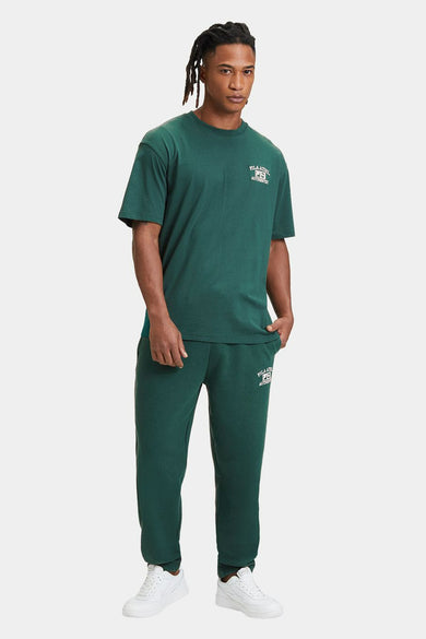 T-shirt vert de mantes courtes FILA, avec logo sur le logo po, combiné avec un pantalon de jogging vert et des baskets blanches.