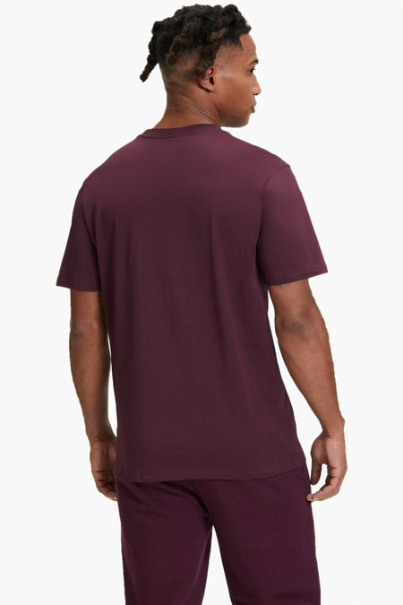 Rood T-shirt met korte mouwen van FILA, gezien van achteren, gedragen met een bordeauxrode broek.