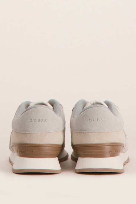 Grijze sneakers van Guess met suède details en logo op de hiel, gezien van achteren.
