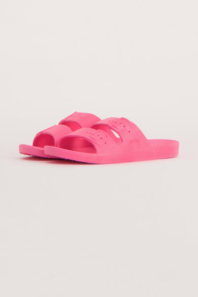 Pantoufles roses de Freedom Moses, avec double sangle et boucles ajustables, sur un fond uni.