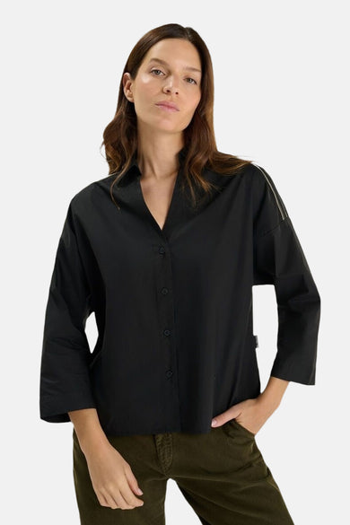 Chemise noire à manches longues de LE TEMPS DES CERISES, portée avec un pantalon vert.