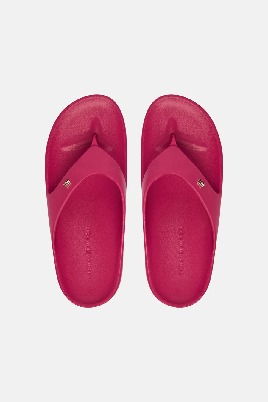 Tongs roses TOMMY JEANS avec un petit logo sur la bride et le nom de la marque en relief sur la semelle intérieure, vus de dessus.