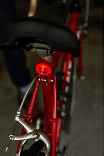 Lampe de vélo rouge de Gentlemen's Hardware, fixée sous un siège noir sur un vélo rouge.