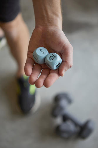 Cadeau multicolore de Gentlemen's Hardware, avec des dés pour les exercices de fitness dans une main, sur un fond flou.