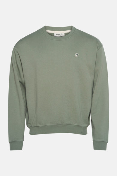 Pull-over vert de POMPEII, avec un petit motif brodé sur la poitrine.