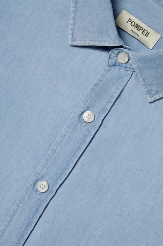Lichtblauw denim jeanshemd van POMPEII, met witte knopen en een kraag.