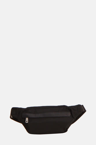 Sac à dos noir de Guess, avec des détails argentés, porté sur la hanche avec un pull gris et un pantalon foncé.