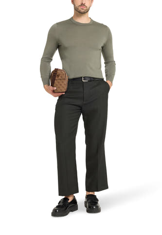 Sac à dos brun de Guess, avec un motif logo, porté par un modèle avec un pantalon et une chemise.