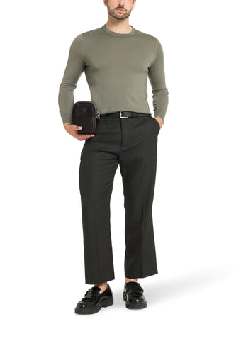 Sac à dos noir de Guess, porté avec un pull vert, un pantalon gris et des loafers noirs.