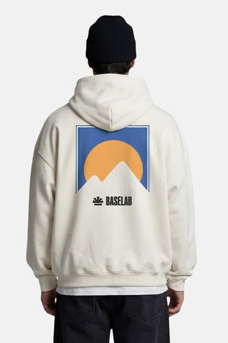 Pull à capuche blanc de la marque BASELAB, avec un logo bleu et orange au dos, porté avec un jean noir.