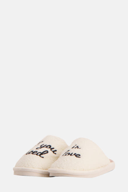 Chaussons écru de FISURA avec le texte "If you need is love" et une douce texture.