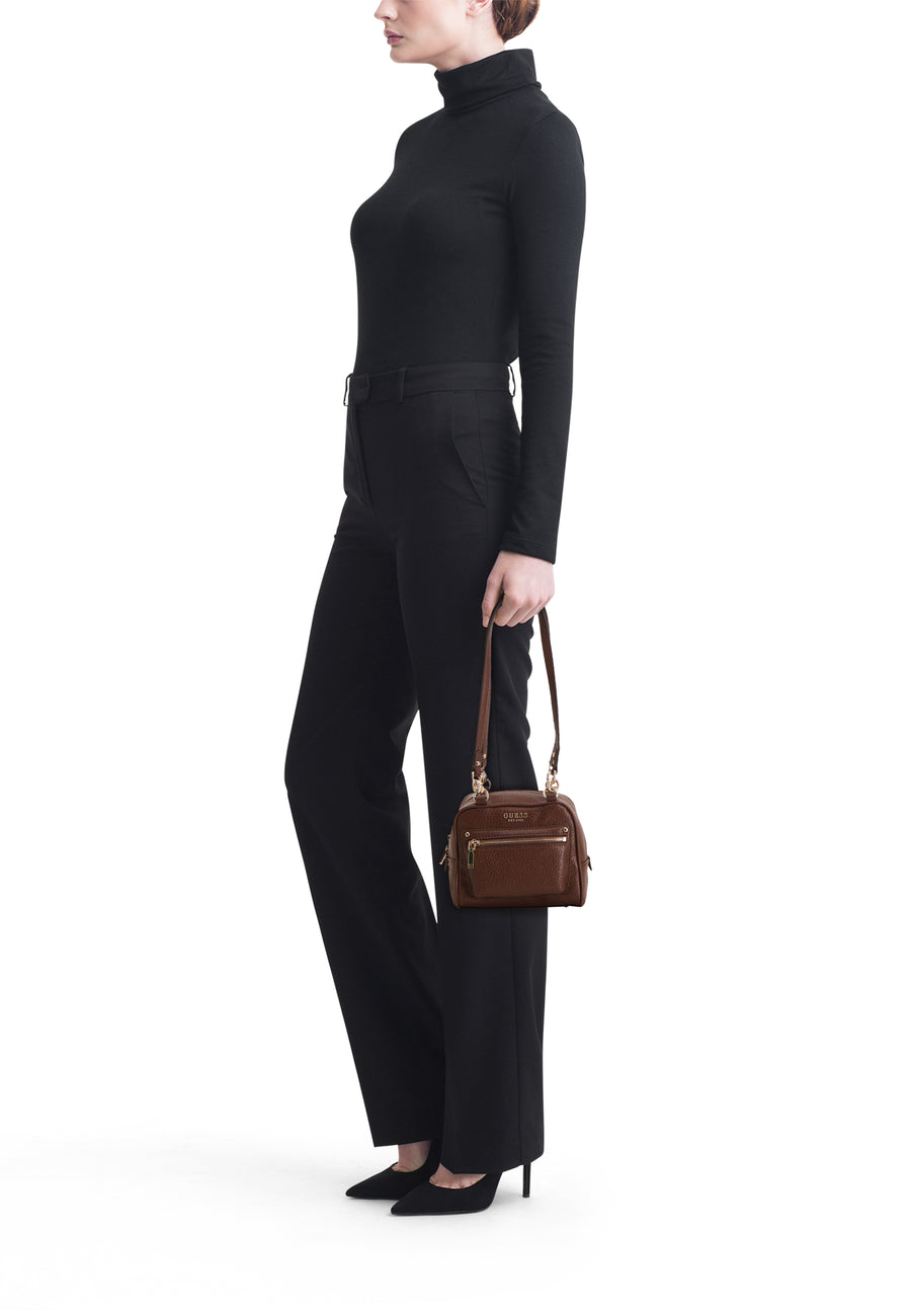 Sac à bandoulière marron Guess, petit modèle avec poche zippée, porté en travers du corps par un mannequin en noir.
